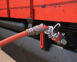 This is a 3D rendered still image from the cad animation displaying a realistic representation of the SpillX fuel system nozzle being inserted into a locomotive. All elements are rendered with realistic textures through Trinity animator's 3D software. The locomotive is displayed in a vibrant red along with the SpillX fuel system nozzle.