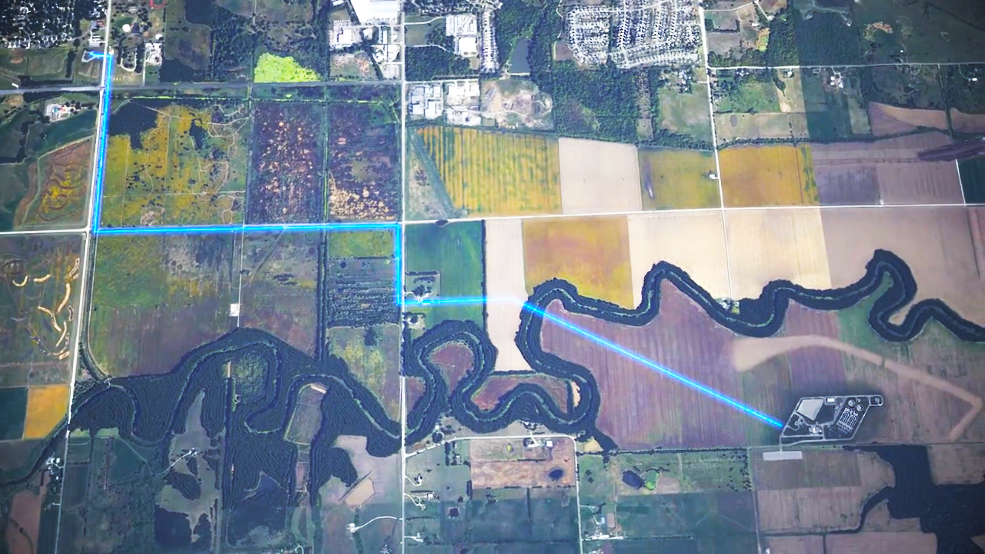 Extremely zoomed out aerial view of both the wastewater plant and pump station. A blue line runs along the roads showing the path that it takes.