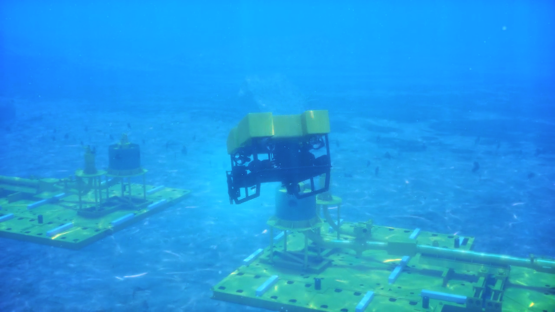 This is a still image of a 3D rendered image from Trinity's animation demonstrating the Oil State's 3 piece clamp system.This particular shot displays the  back end of the ROV as it is dives toward the base structures of the pipelines.